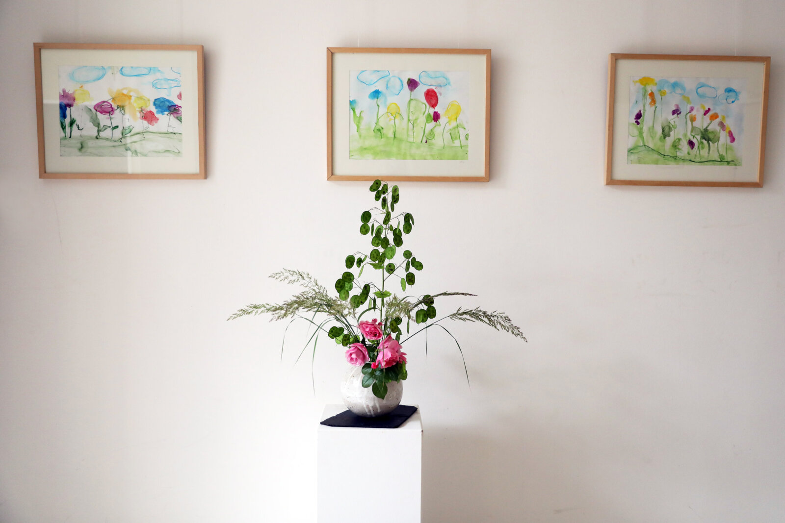 bild-parzival-schule-berlin-aktuelles-vase-mit-bildern eine Vase vor einer Wand mit 3 Bilderrahmen